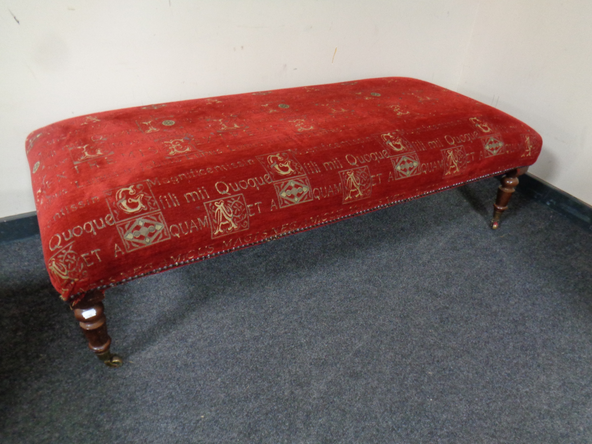 A contemporary oversized footstool upholstered in a red fabric