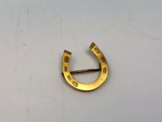 An antique gold horseshoe brooch
