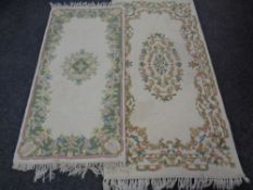 Two Indian floral patterned fringed rugs on cream ground