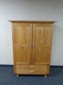 A contemporary oak double door child's wardrobe fitted two drawers beneath