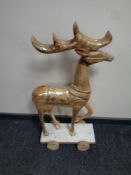 A carved wooden reindeer on wheeled base