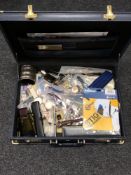 A briefcase containing modern wristwatches, two vintage silver-cased watch faces, pens,