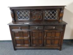 An Ercol solid elm and beech triple door buffet back sideboard in an antique finish