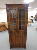 A good quality oak linen fold double leaded glass door corner display cabinet,