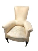 A Regency armchair, with curved and shaped back, the front raised with brass cappings and castors,