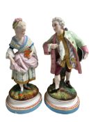 A pair of Continental bisque figures modelled as a Lady & Gentleman in traditional dress,