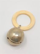 A silver rattle with ivory teething ring,