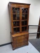 A reproduction Regency style mahogany double door bookcase fitted three drawers and a slide beneath