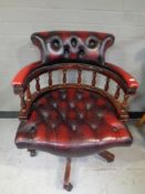 A captain's desk chair upholstered in red button leather