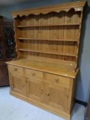 A stripped pine triple door welsh dresser fitted three drawers,
