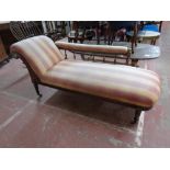An Edwardian oak framed chaise longue upholstered in a striped fabric with two matching cushions