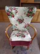 A 20th century beech framed wingback armchair upholstered in a floral fabric