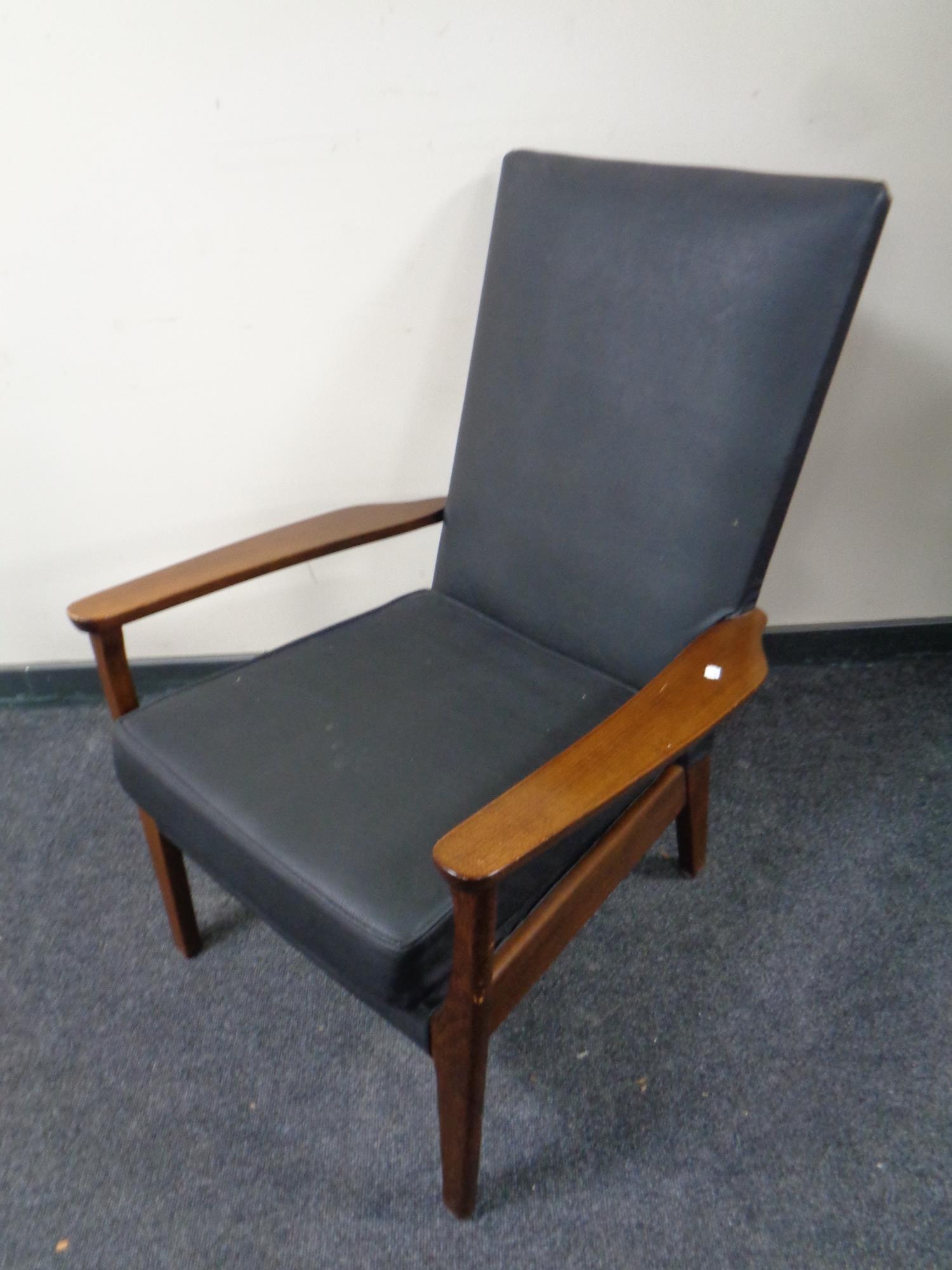 A mid 20th century teak armchair upholstered in black vinyl