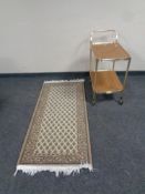 A two tier tea trolley together with a fringed woolen rug