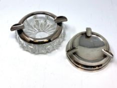 A silver ashtray and another silver mounted glass ashtray.