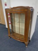 A 20th century walnut bow fronted single door display cabinet on Queen Anne legs