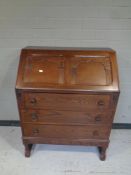 A carved oak writing bureau fitted three drawers