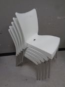 A set of five white molded plastic stacking chairs