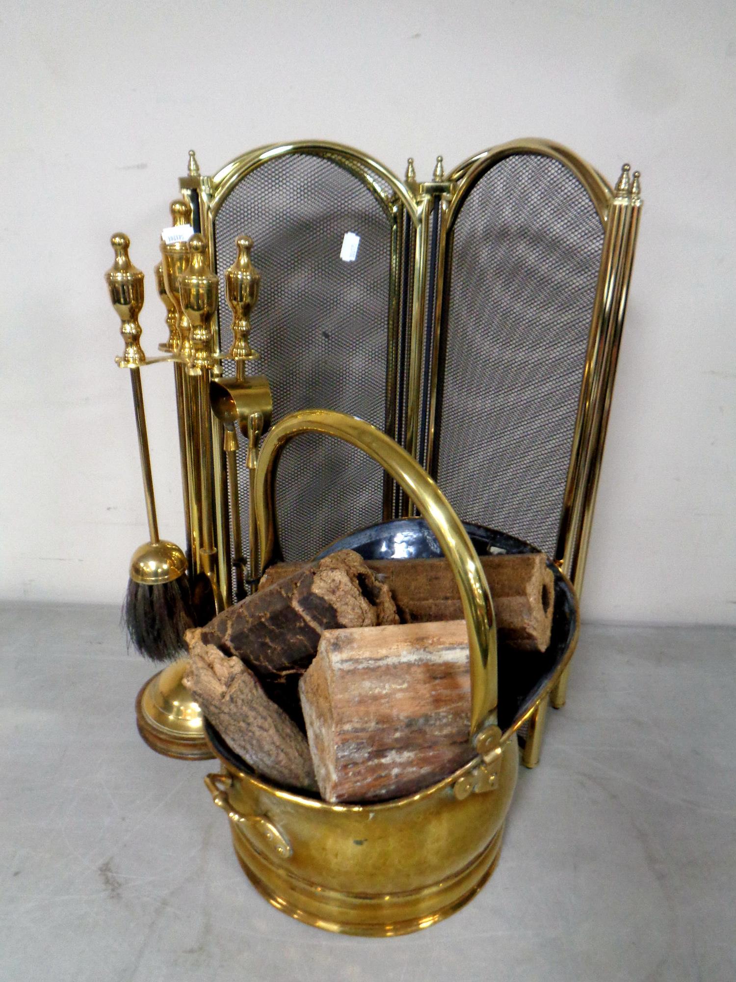 A four piece brass companion set on stand together with a brass swing handled coal bucket and a