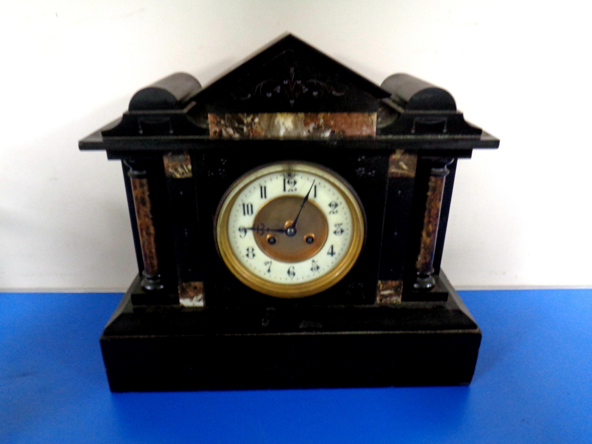 An antique black slate and marble mantel clock