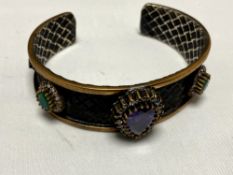 A silver vintage bangle set with amethyst, emerald,