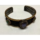 A silver vintage bangle set with amethyst, emerald,