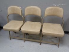 A set of three 20th century metal and vinyl connecting folding chairs