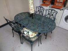 A cast metal patio table together with four matching armchairs, parasol,
