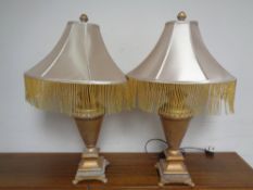 A pair of contemporary classical table lamps with tasselled shades