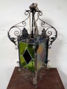 An antique wrought iron hanging lantern light fitting with four stained glass panels (as found)