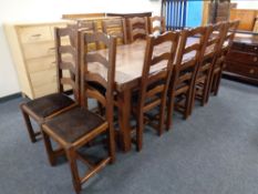 A contemporary oak farmhouse kitchen table with two extension leaves and ten ladder back chairs,