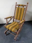 An early 20th century continental oak rocking chair upholstered in a striped fabric