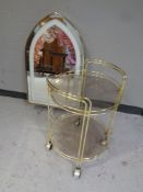 A brass and glass two tier drinks trolley together with a brass framed arch topped twin sided