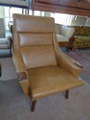 A 1970s Danish armchair upholstered in a brown vinyl on teak legs,
