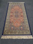 A machine made Persian design fringed rug on blue ground,