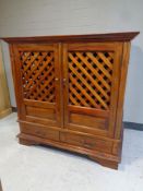 An eastern hardwood double door TV cabinet fitted two drawers beneath