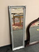 A narrow silvered framed mirror,