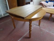 A circular blonde oak extending dining table with two leaves
