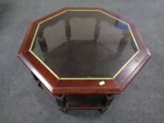 A contemporary octagonal coffee table with under shelf in a mahogany finish