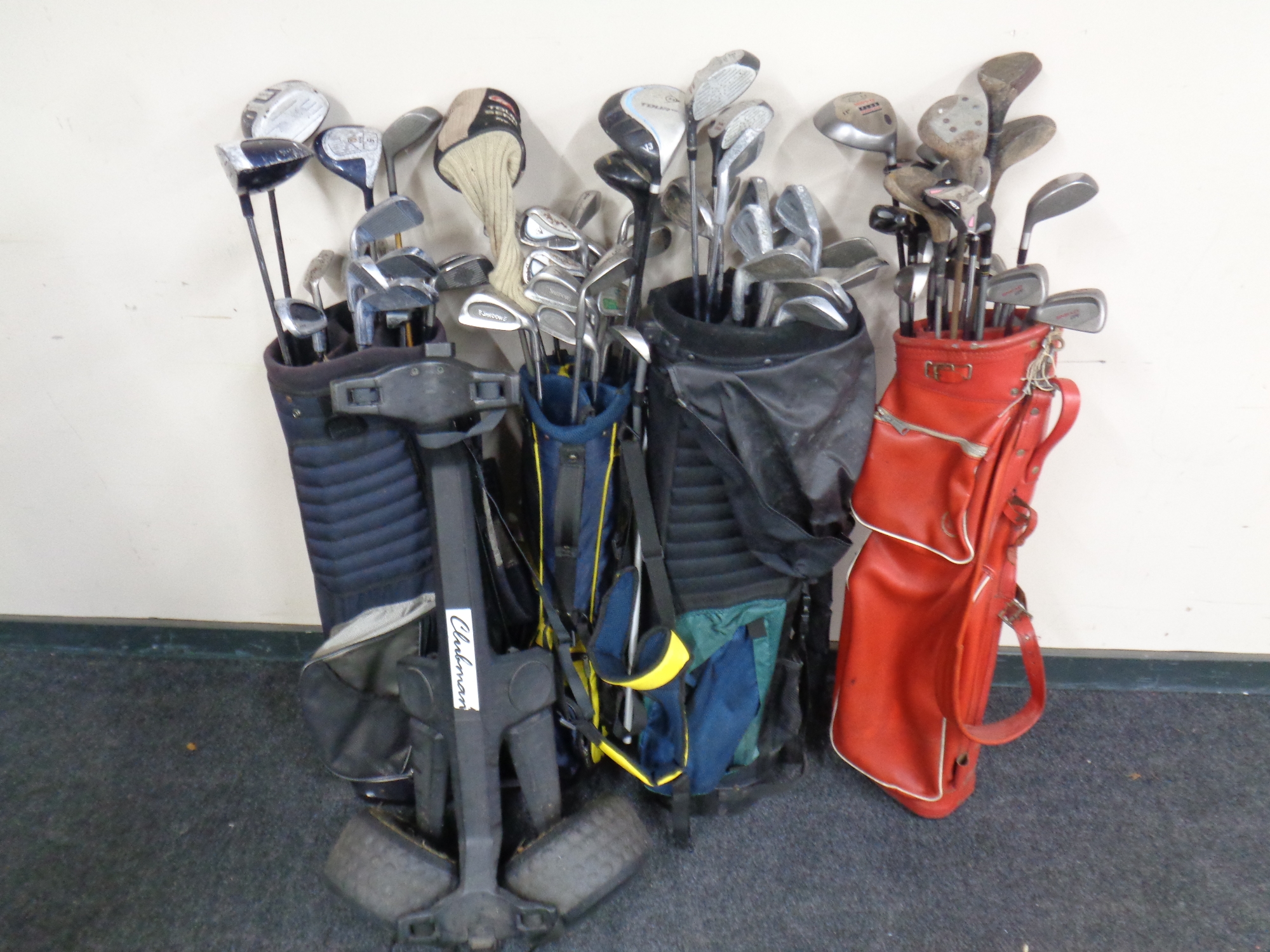 Four golf bags containing a large quantity of assorted irons,