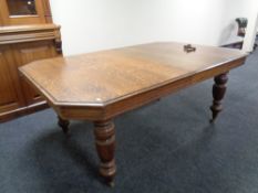 A 19th century octagonal oak wind out dining table with leaf and handle