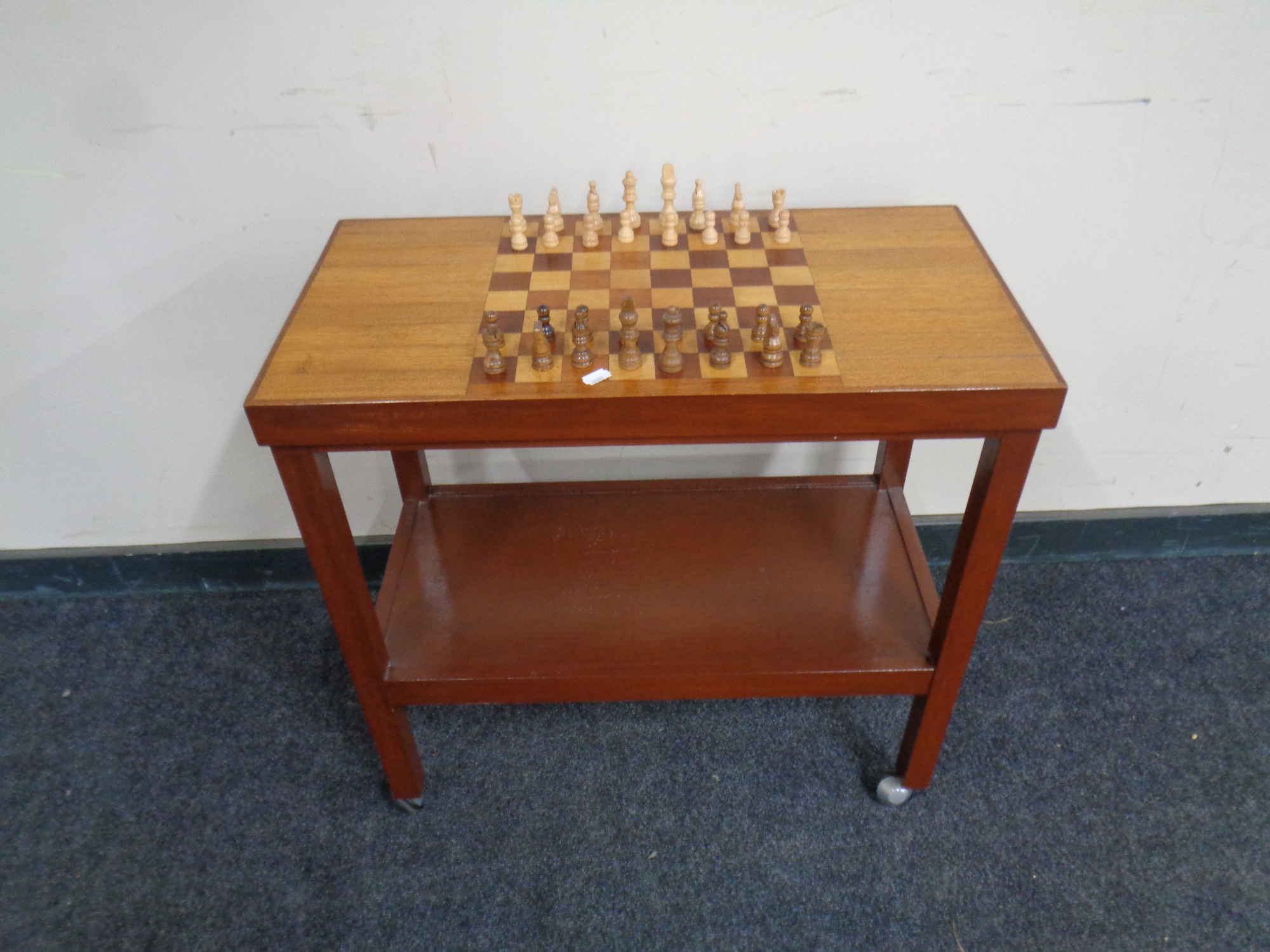 A 20th century two tier tea trolley with chessboard top and pieces