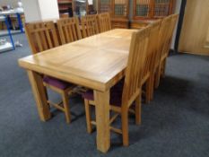 A contemporary oak dining table together with a set of eight rail back chairs