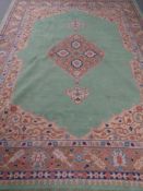 A 20th century fringed woolen carpet of Persian design on green ground