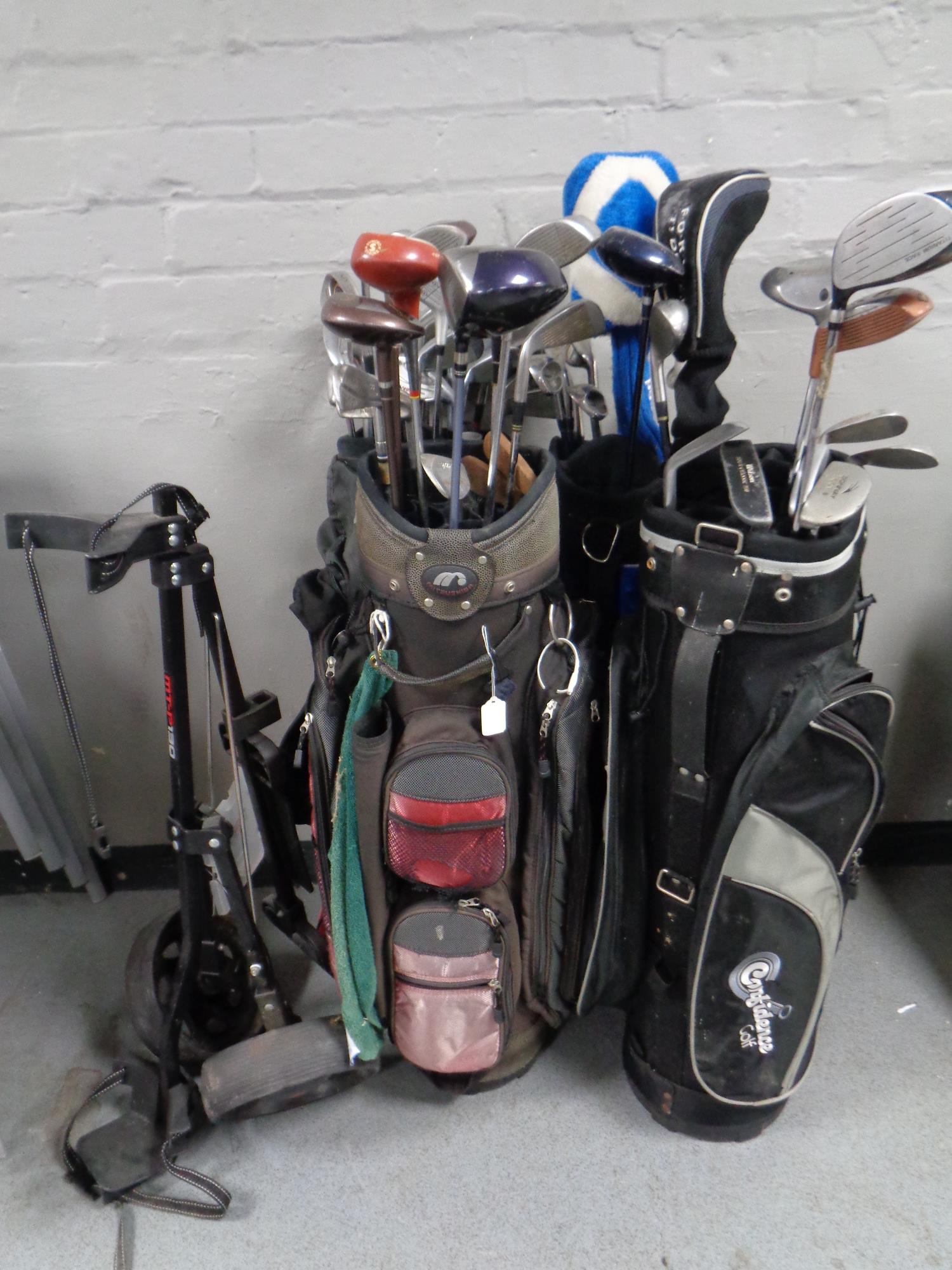Four golf bags containing a quantity of assorted irons,