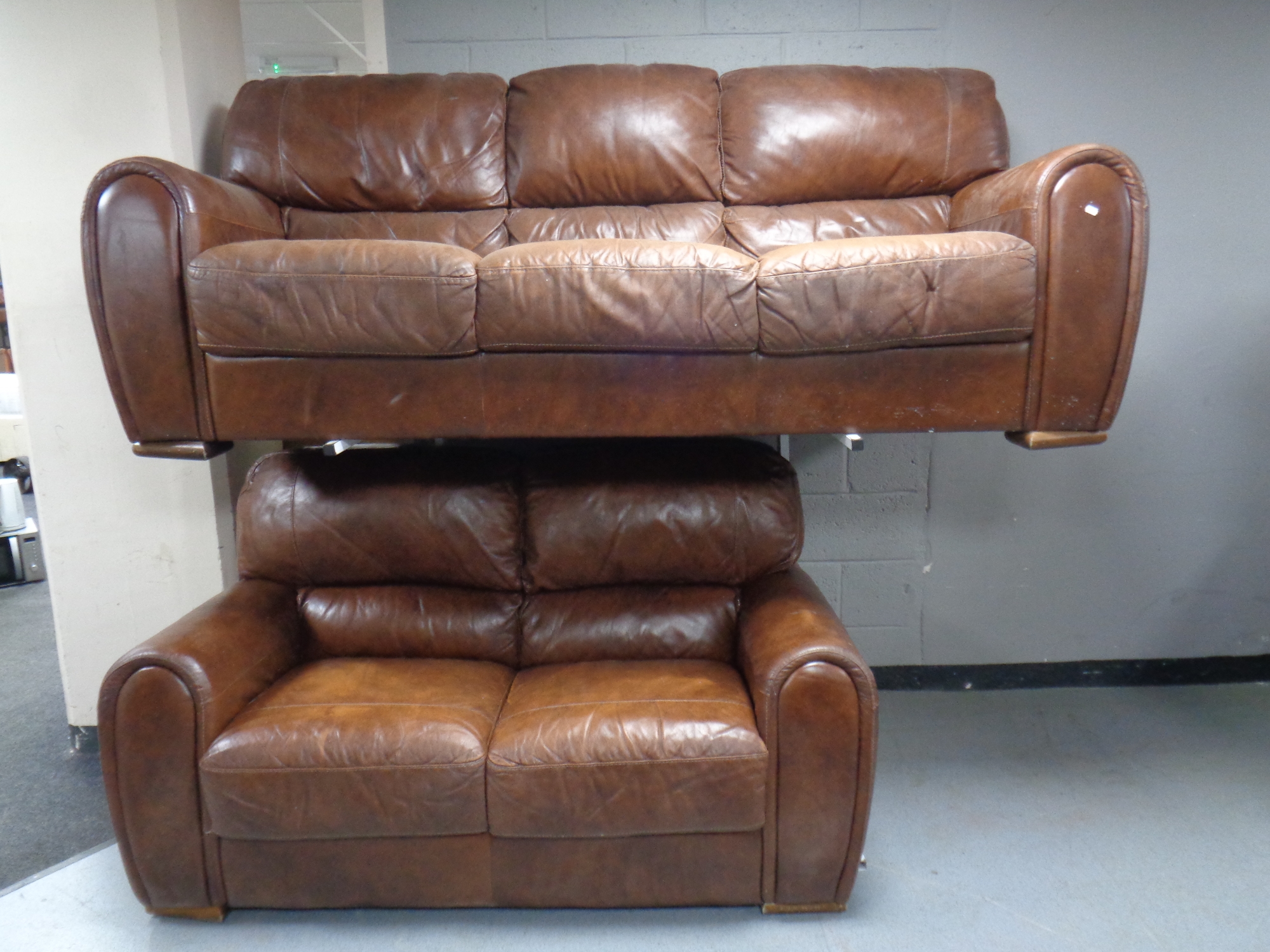 A three seater settee together with matching two seater settee upholstered in brown leather