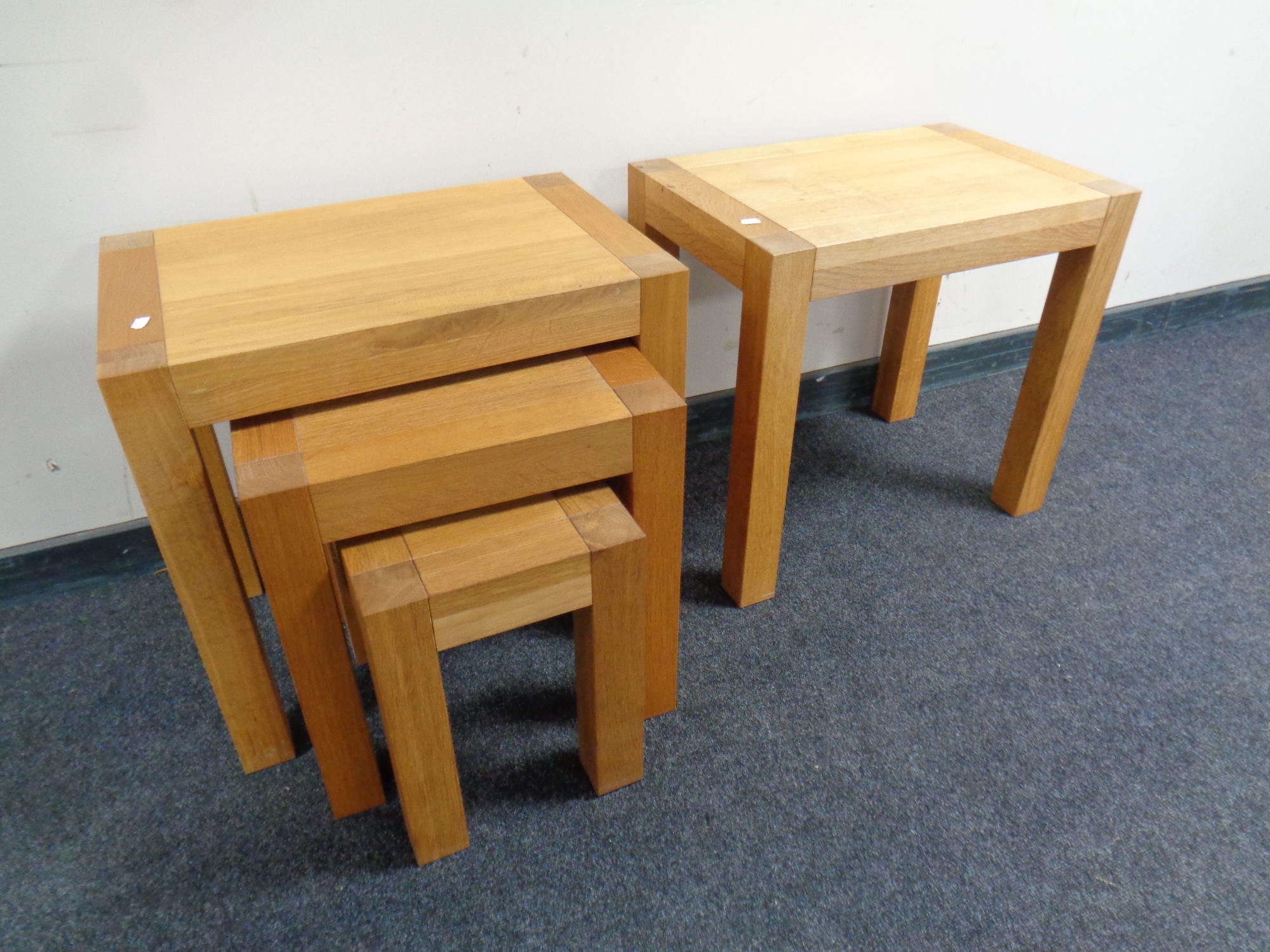 A nest of three contemporary oak tables together with a matching oak occasional table