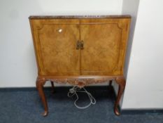 A burr walnut double door cocktail cabinet on raised Queen Anne legs