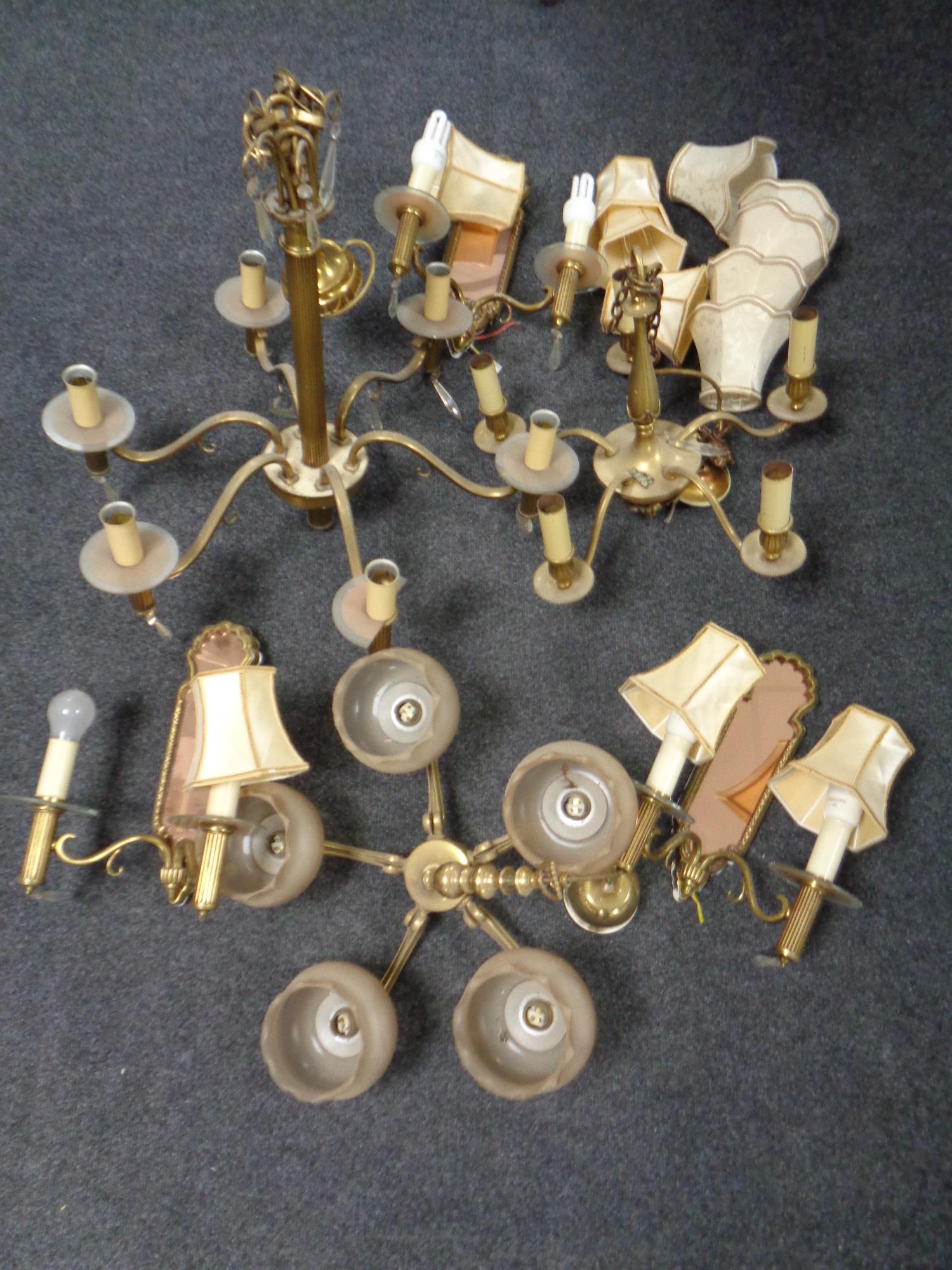 A plastic water tank containing a large quantity of assorted brass chandeliers and wall lights