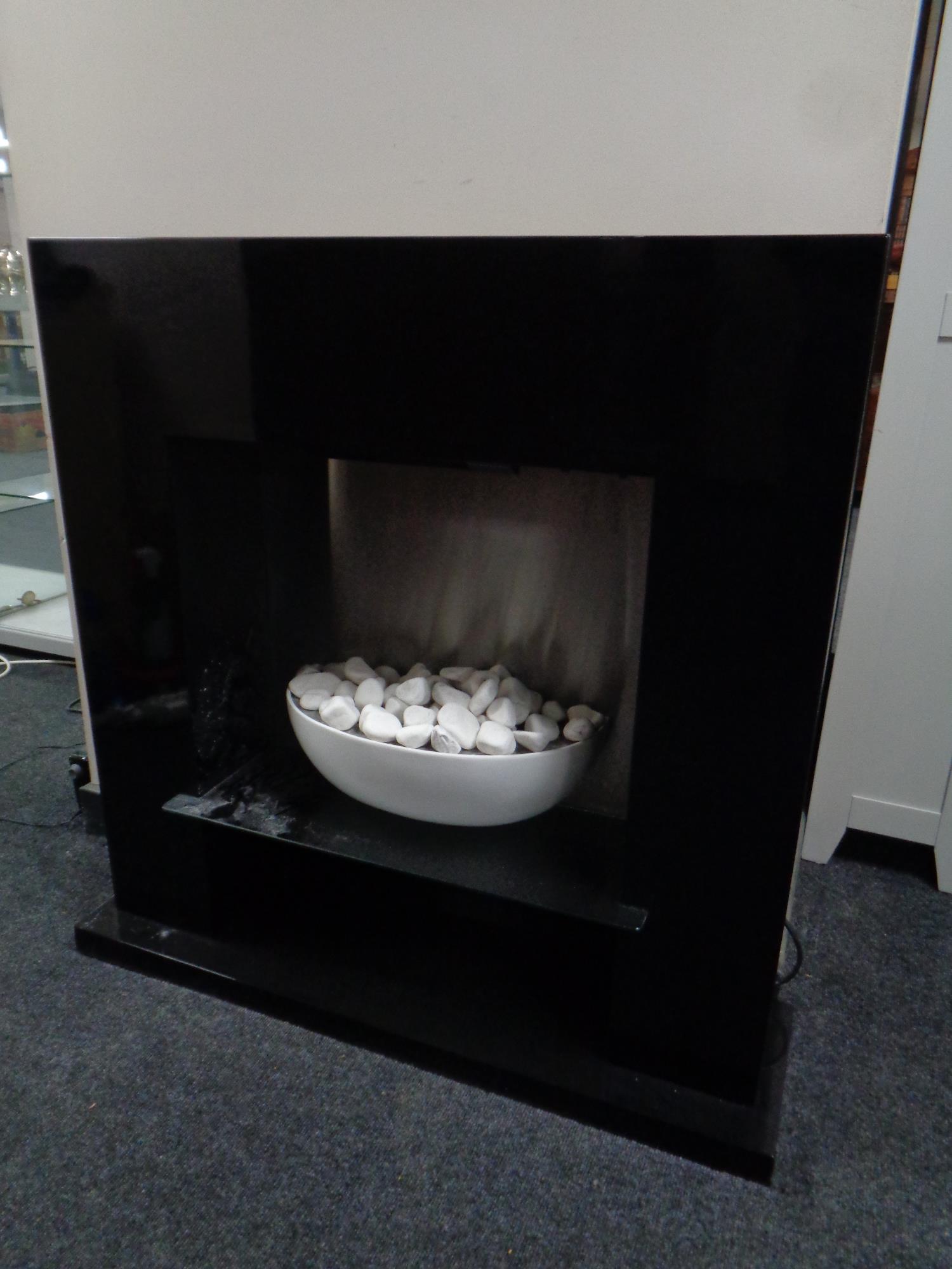 A contemporary electric fire in a black high gloss surround